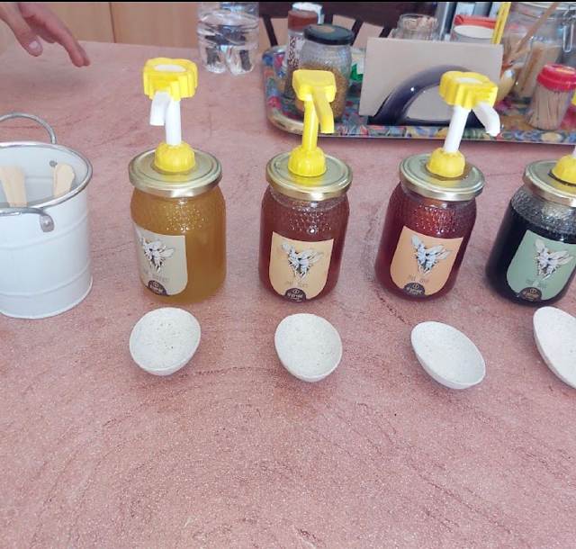 Jars of local honey with tasting spoons laid out on a table