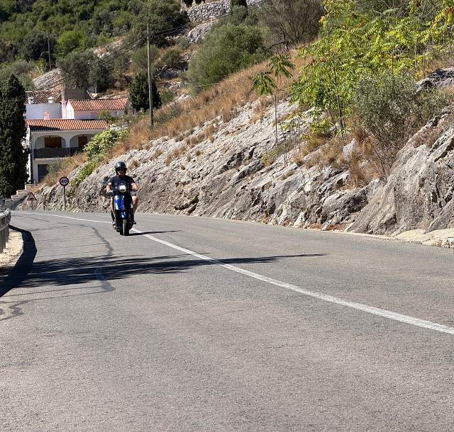 A Vespa coming down the mountain road past a village